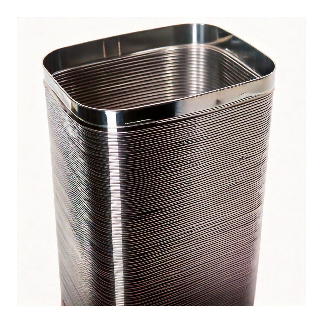 A close-up of the Rectangle Chimney Liner, made of 316Ti stainless steel, reveals its ribbed, metallic design with rounded edges. The lighting highlights its shiny surface and horizontal pattern, emphasizing its durable and reflective qualities.